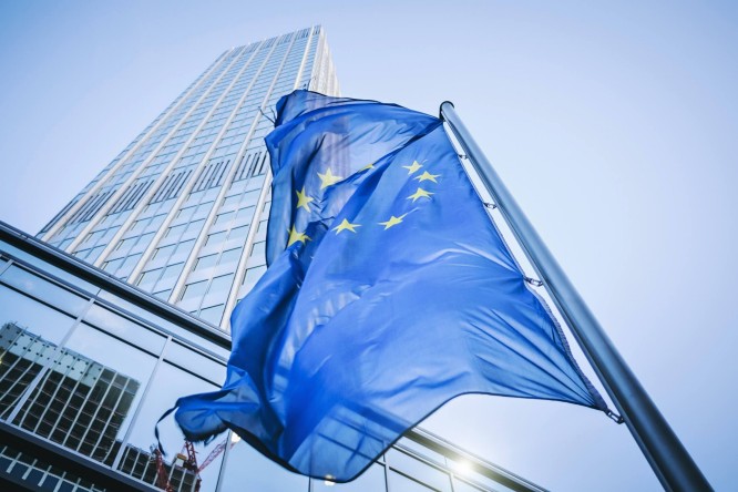 An EU flag visible in front of skyscrapers, European Investment Bank