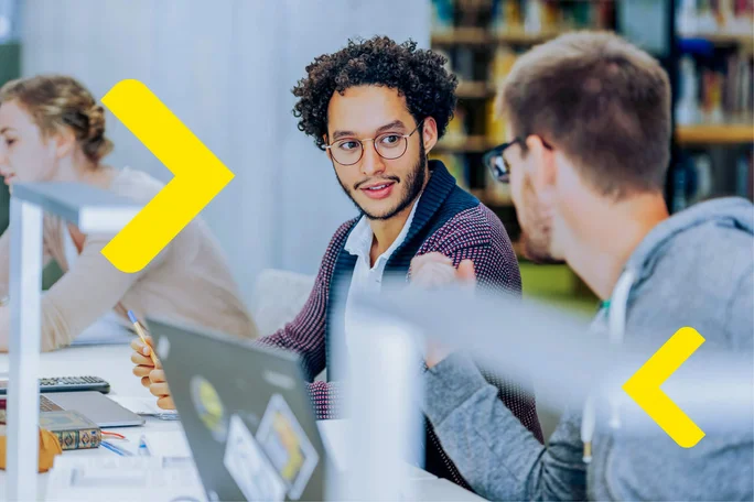 A team engaged in active collaboration within an office environment, utilizing laptops and documents. The setting fosters communication and teamwork, enhanced by bright yellow directional arrows.