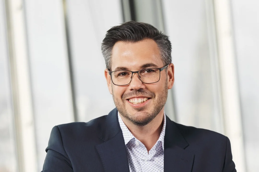 Porträt von Sebastian Kupka – Director of Supply Chain Finance bei RBI, © eap.at, lächelt in einer Büroumgebung und steht für Führungsstärke und Innovation in der Finanzstrategie.