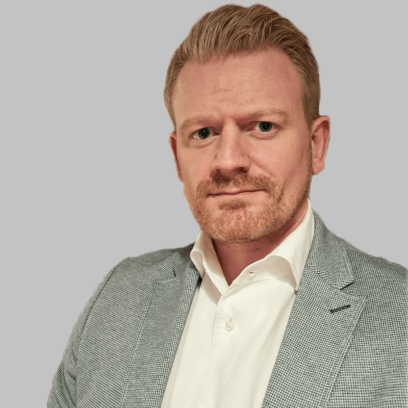 Eine gut gekleidete Person in einem grauen Blazer und einem weißen Hemd, die ein gepflegtes und professionelles Erscheinungsbild zeigt.