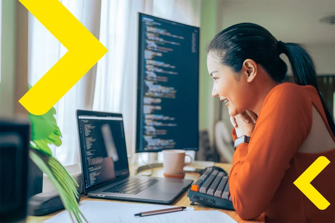A programmer deeply engaged in coding, using a dual-monitor setup in a well-lit workspace. The scene reflects concentration and dedication to software development. Branded in yellow Raiffeisen arrows.