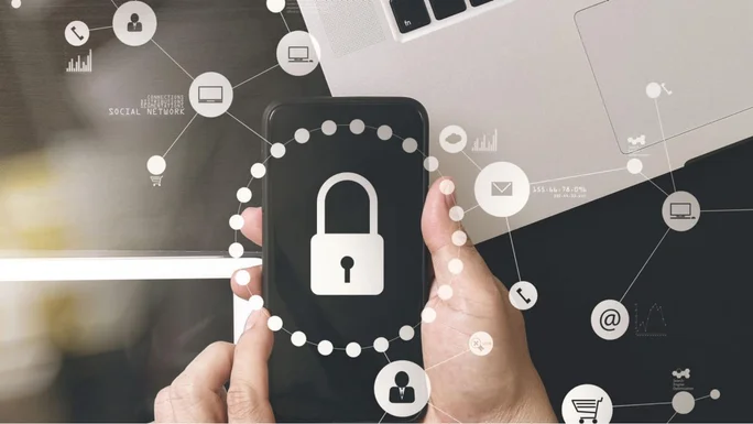 Eine Person hält ein Smartphone mit einem Schlosssymbol, umgeben von Symbolen für digitale Sicherheit und Konnektivität, im Hintergrund ist ein Laptop zu sehen.