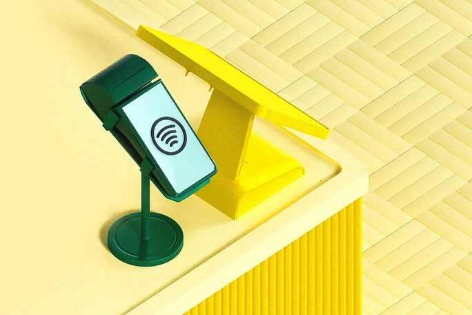 Ein stilvolles, modernes kontaktloses Zahlungsterminal in Grün und Gelb steht auf einer Theke und ist bereit für digitale Transaktionen. Das Bild zeigt innovative Kassentechnologie in einem hellen, minimalistischen Ambiente.