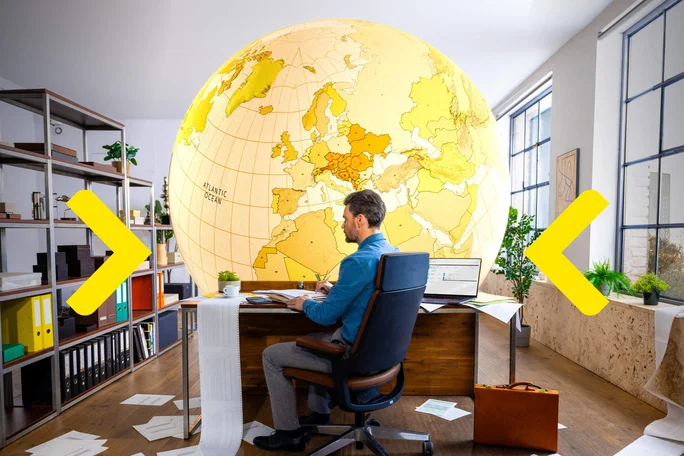 Ein Geschäftsmann sitzt an einem Schreibtisch, umgeben von Finanzdokumenten, und analysiert globale Daten vor dem Hintergrund einer riesigen Weltkarte.