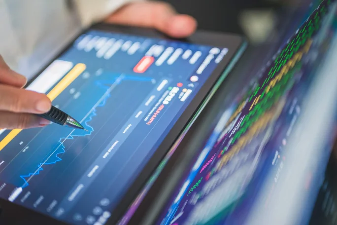 Dieses Bild zeigt eine Nahaufnahme einer Person, die mit einem Stift Börsendaten auf einem Tablet analysiert. Die Anzeige von Diagrammen und Grafiken ist lebendig. Es verdeutlicht die Integration von Technologie in Finanzanalyse und Handel und demonstriert die Möglichkeit zur Entscheidungsfindung in Echtzeit.