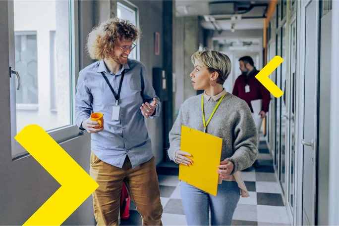 Colleagues discussing ideas while walking through a vibrant office corridor.