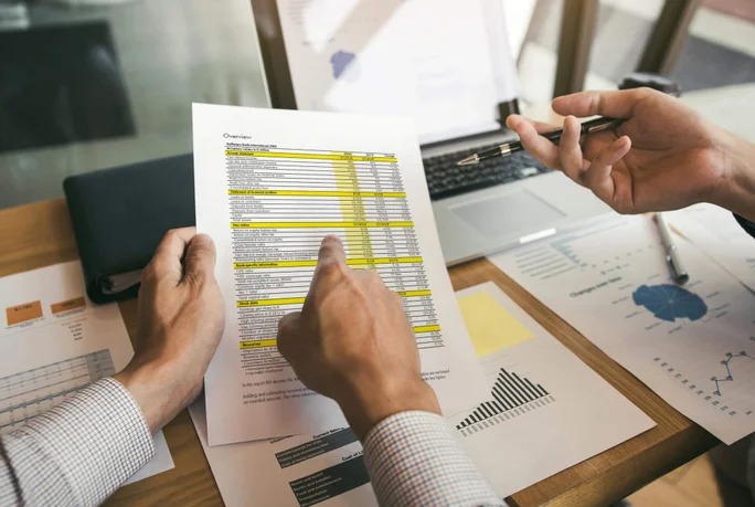 Zwei Fachleute diskutieren ausführlich über Finanzdokumente und -diagramme und konzentrieren sich dabei auf die strategische Geschäftsanalyse und -planung.