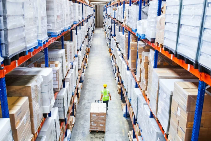 A person walking through a storage hall with lots of packages