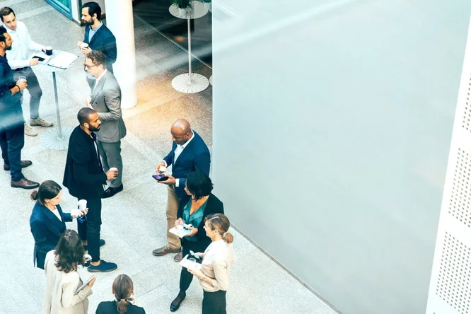 Eine Gruppe von Geschäftsleuten vernetzt sich und führt Gespräche während einer Firmenveranstaltung – hebt Zusammenarbeit, Beziehungsaufbau und Möglichkeiten zur beruflichen Weiterentwicklung hervor.