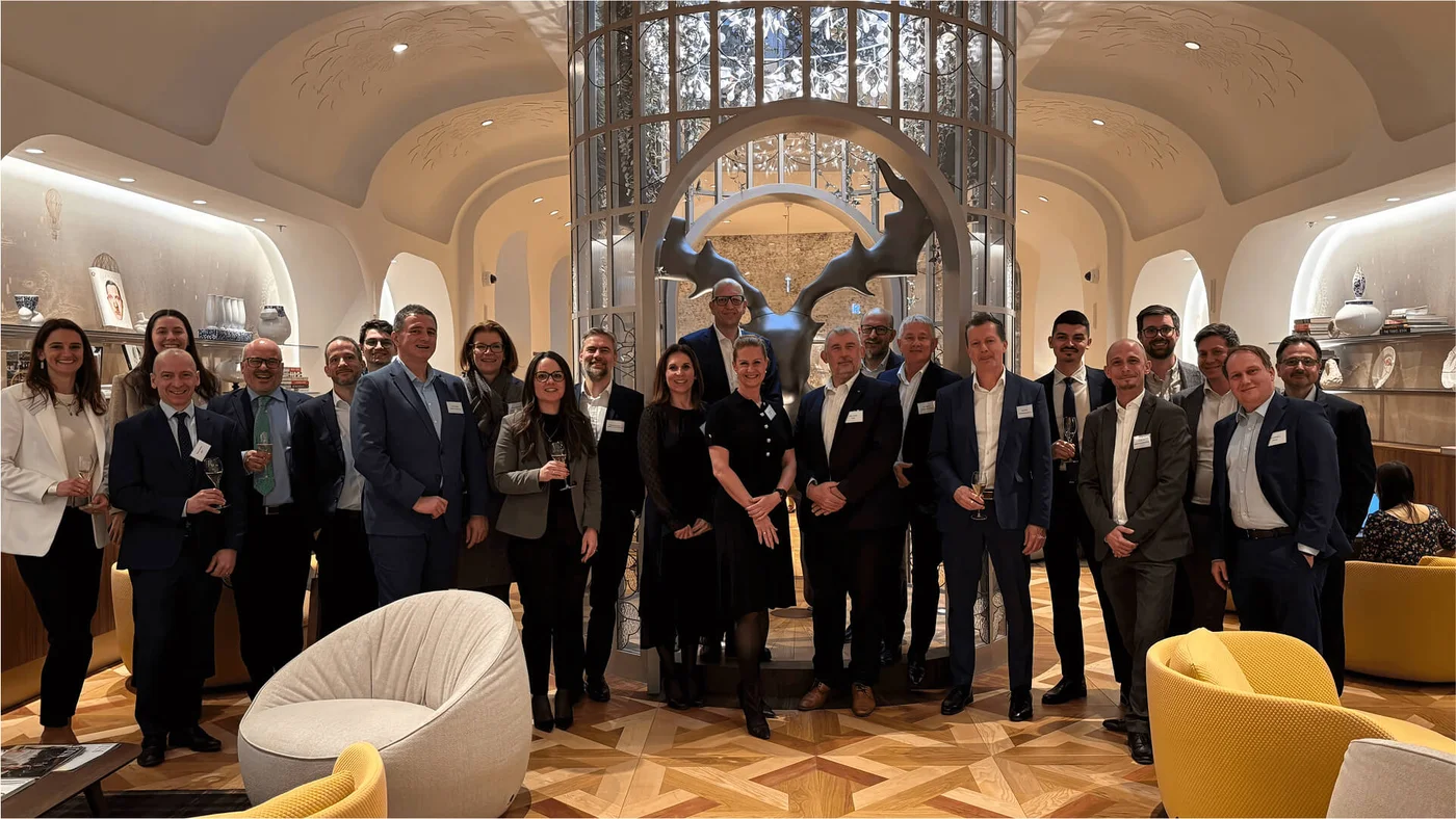 A group of professionals gathered in a stylish venue with elegant décor, including arched ceilings and intricate lighting. The event features socializing and networking activities.