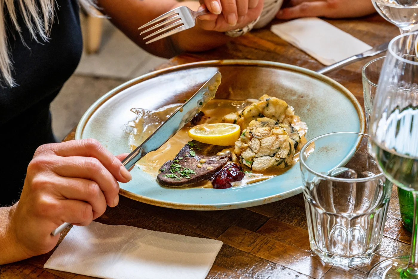 Girl (part of person) eating traditionally czech food "svickova" sauce, beef and dumpling in restaurant.
