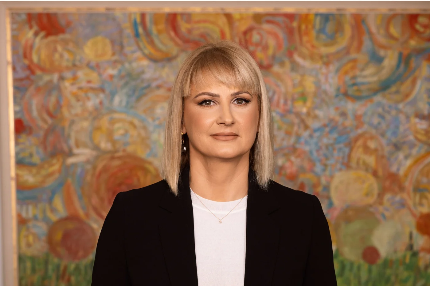 Porträtbild von Anita Kovacic, CEO der Raiffeisen Bank Kosovo, vor einem Gemälde.