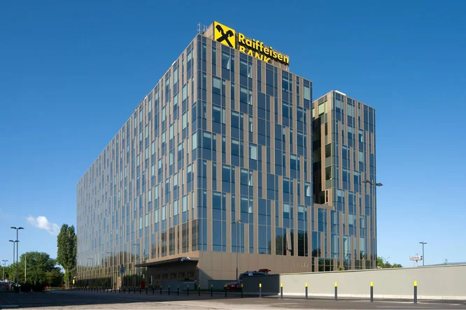 Modernes Bürogebäude der Raiffeisen Bank Serbien mit spiegelnden Glasfassaden und dem ikonischen gelben Logo vor klarem, blauem Himmel.