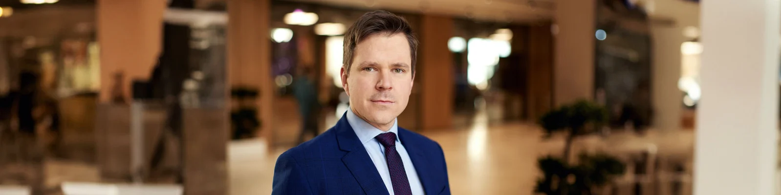 Ein professionelles Portrait eines Raiffeisen Bank Executives im blauen Anzug, der selbstbewusst in einer modernen Büroumgebung posiert.