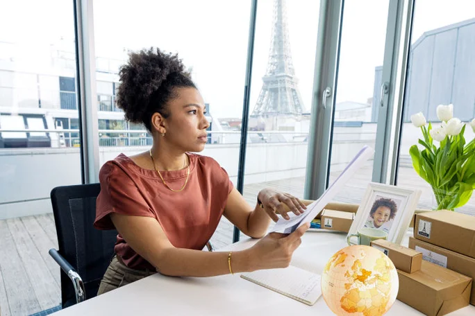 Woman sitting at desk with Eiffle Tower in the background and a globe on the desk
