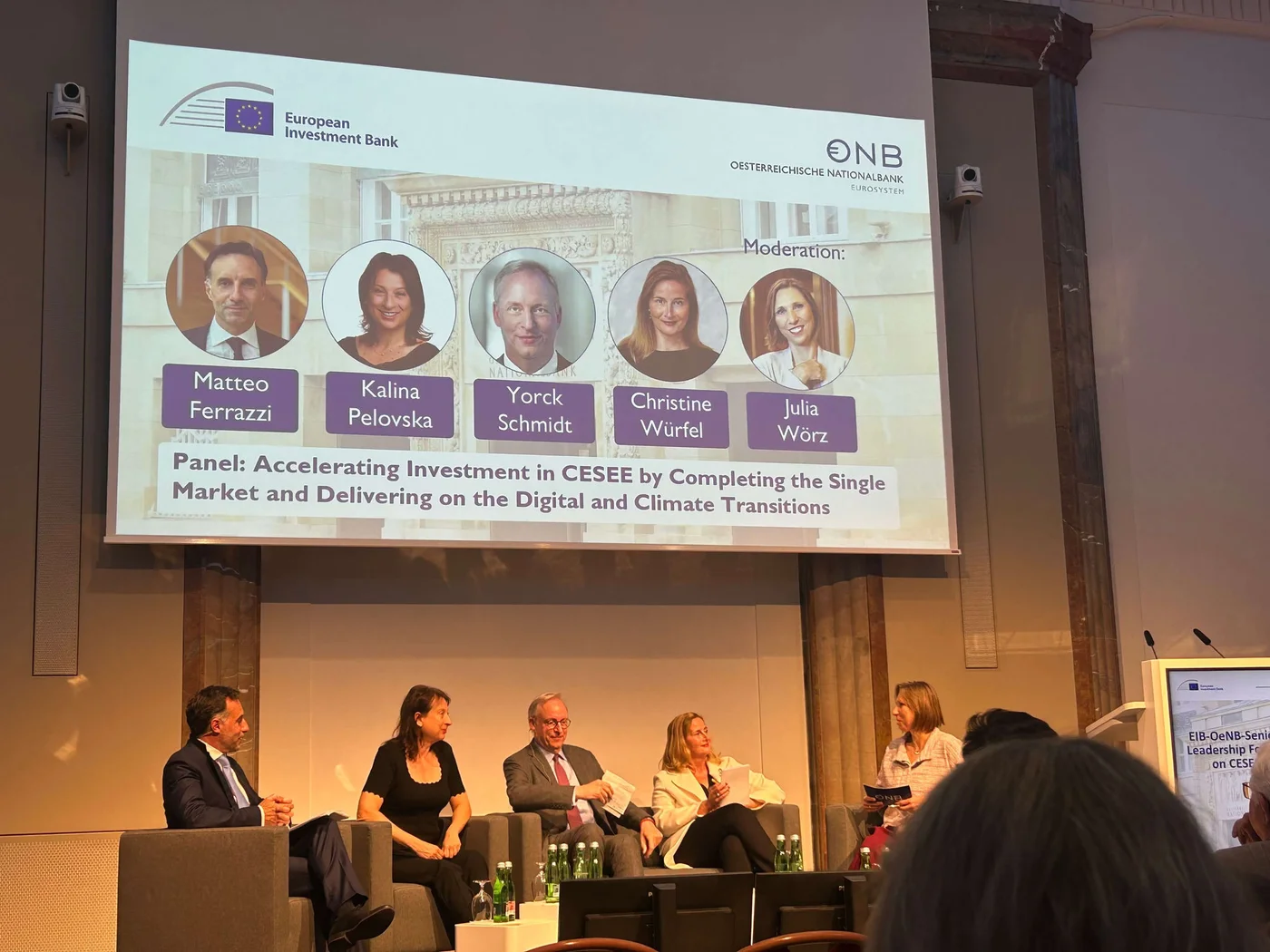 A professional panel discussion hosted by the European Investment Bank and Oesterreichische Nationalbank. The event focuses on accelerating investment in CESEE regions, addressing digital and climate transitions. The panelists are seated on stage with a large screen displaying their names and discussion topics. Visible text includes 'European Investment Bank' and 'Oesterreichische Nationalbank'.