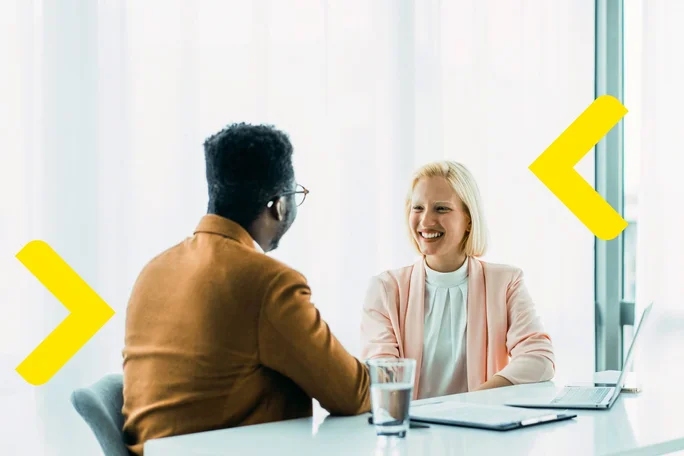 Zwei Personen führen an einem modernen Bürotisch ein konzentriertes Geschäftsgespräch, bei dem Zusammenarbeit und strategische Planung im Vordergrund stehen.