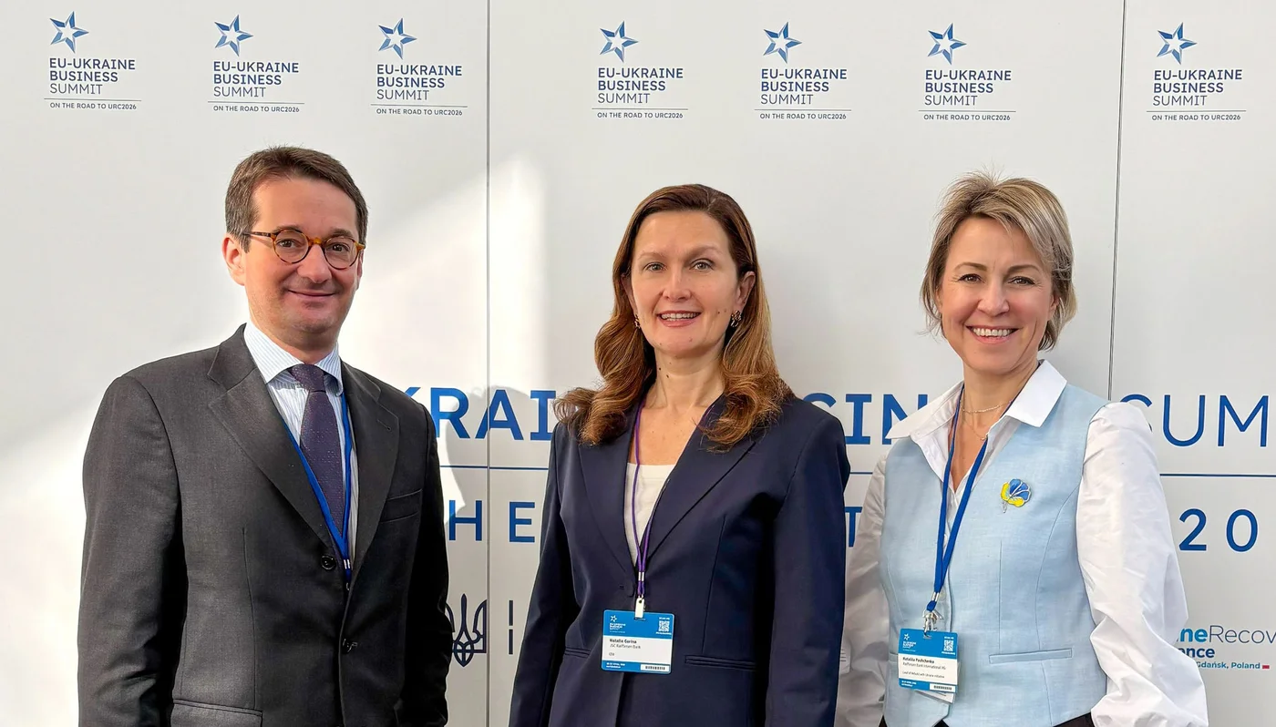 One man, two women in front of a wall at a conference