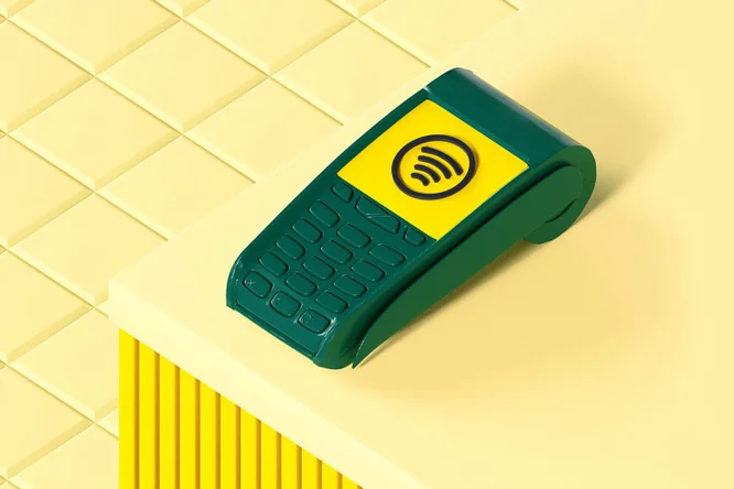 Auf einem gelben Tresen steht ein elegantes, grün-gelbes kontaktloses Kartenlesegerät, das moderne Zahlungstechnologie für sichere und bequeme Transaktionen im Einzelhandel vorführt.