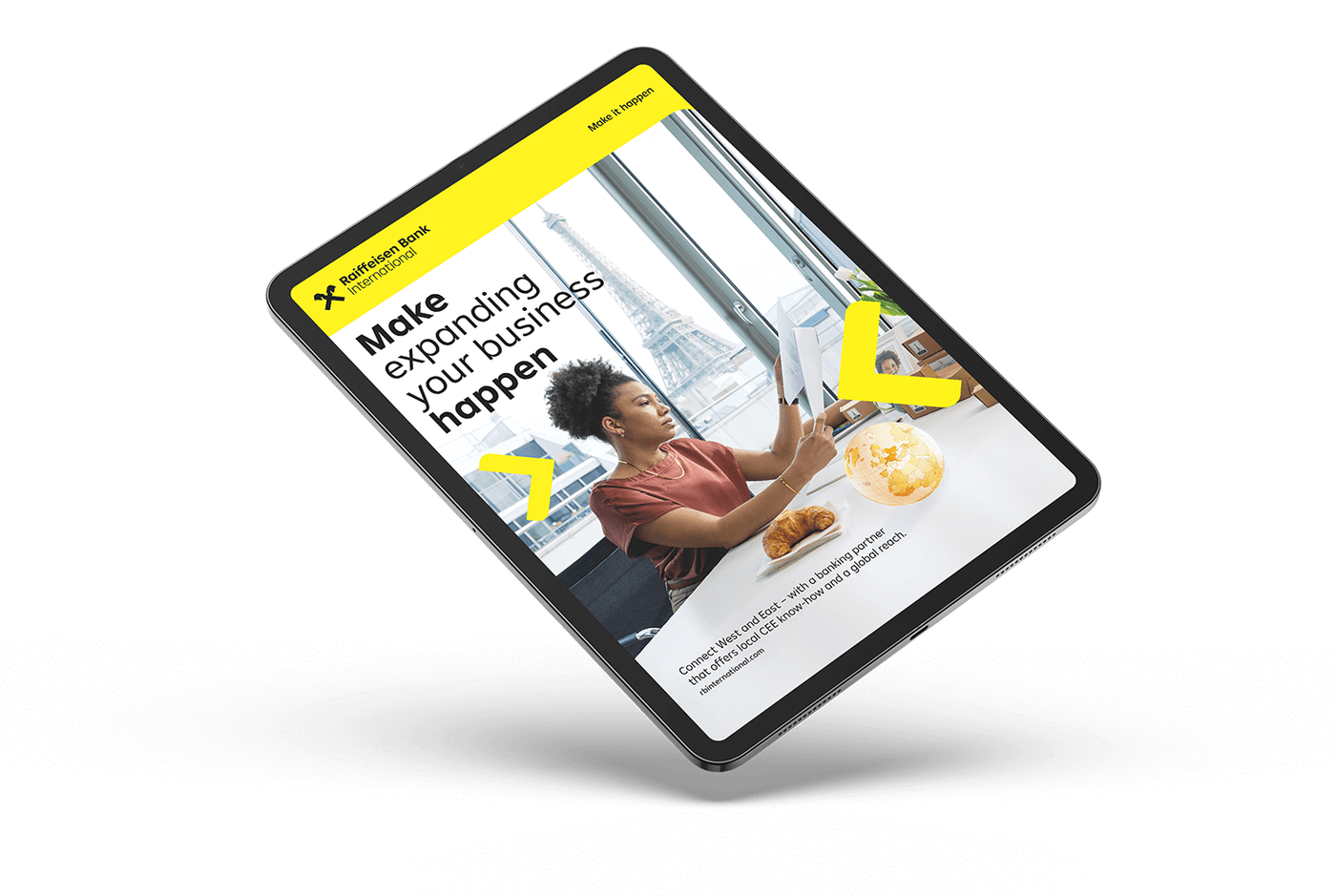 A tablet showing a promotional page with a woman working at a desk, the Eiffel Tower in the background, and branding elements of Raiffeisen Bank.