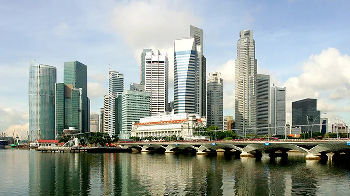 Lebendige Skyline moderner Wolkenkratzer an einem Fluss, beeindruckende Architektur spiegelt sich im Wasser unter klarem Himmel wider.