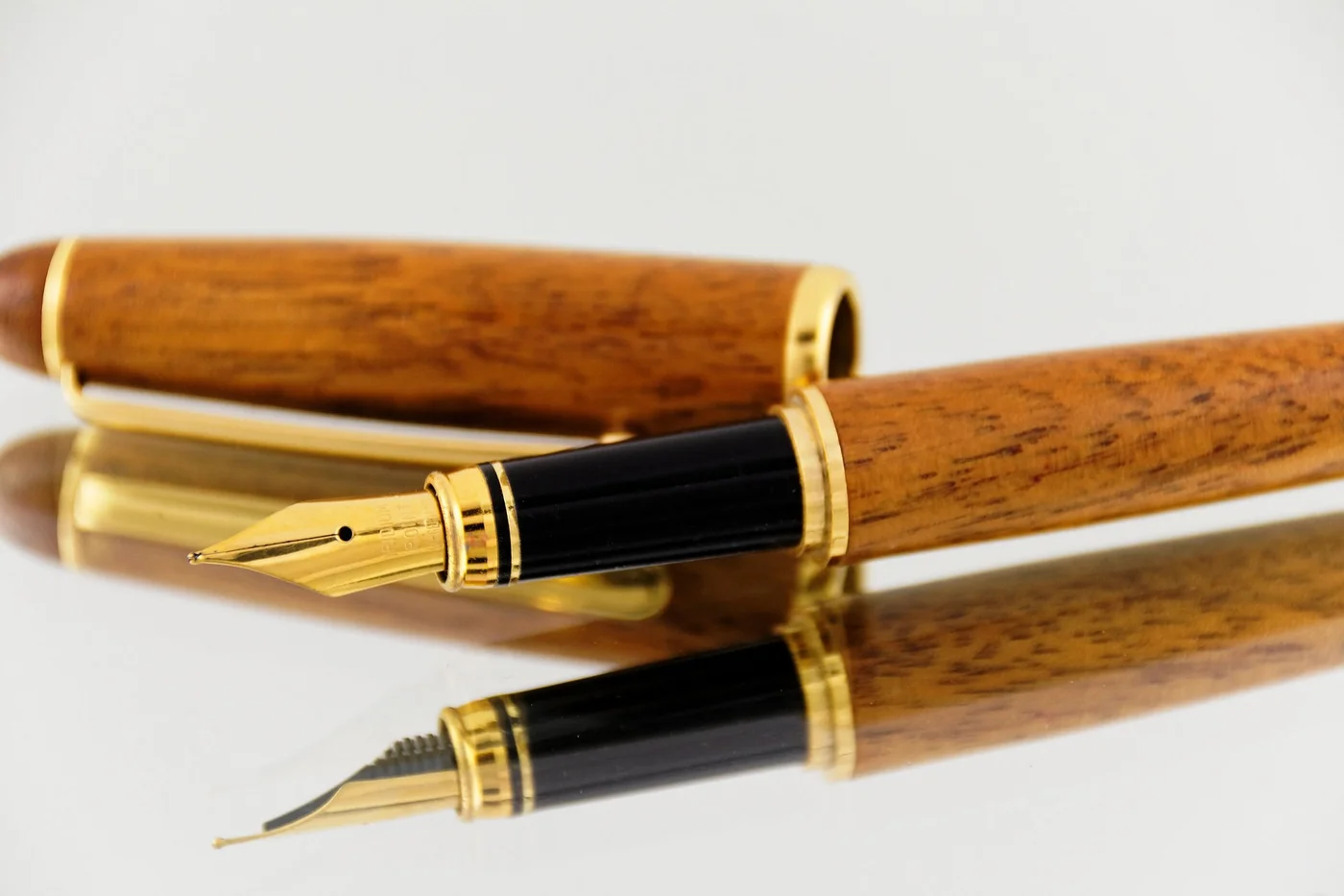 Wooden fountain pen with gold ending in a white backround and white table