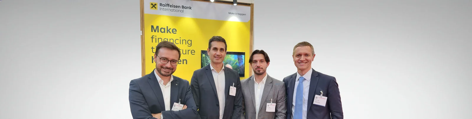 Eine Gruppe von Fachleuten der Raiffeisen Bank International steht gemeinsam bei einer Veranstaltung und demonstriert ihr Engagement, die Finanzierung der Zukunft mit innovativen Lösungen voranzutreiben.