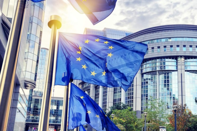 Two EU flags visible in front of skyscrapers,