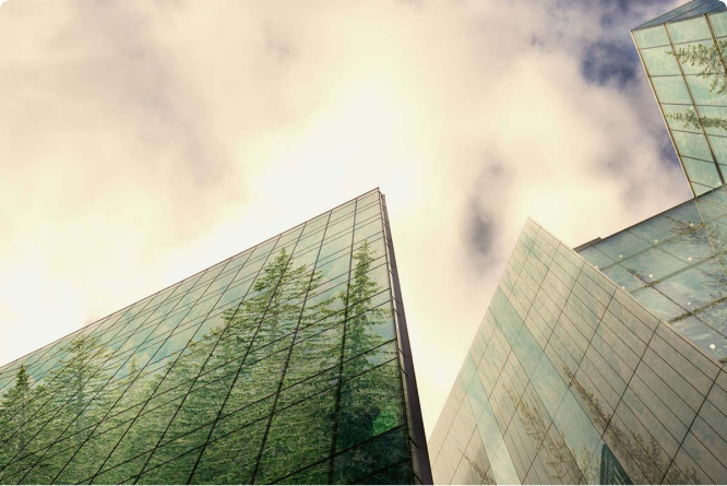 Buidlings made of glass mirroring trees, clouded sky