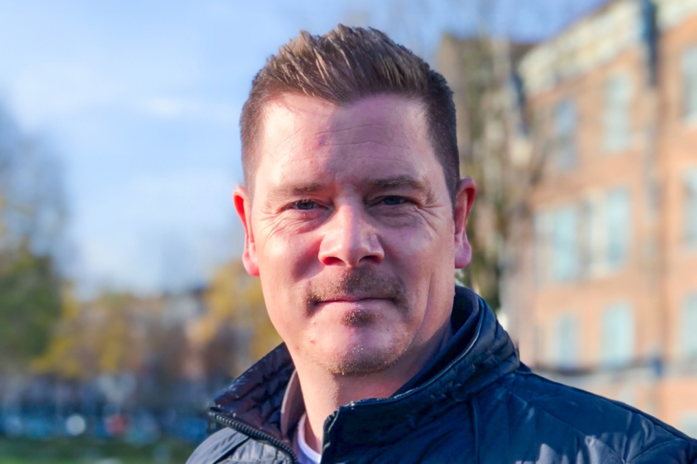 Close-up portrait of a male professional in an urban setting, representing expertise in sustainable finance and business leadership