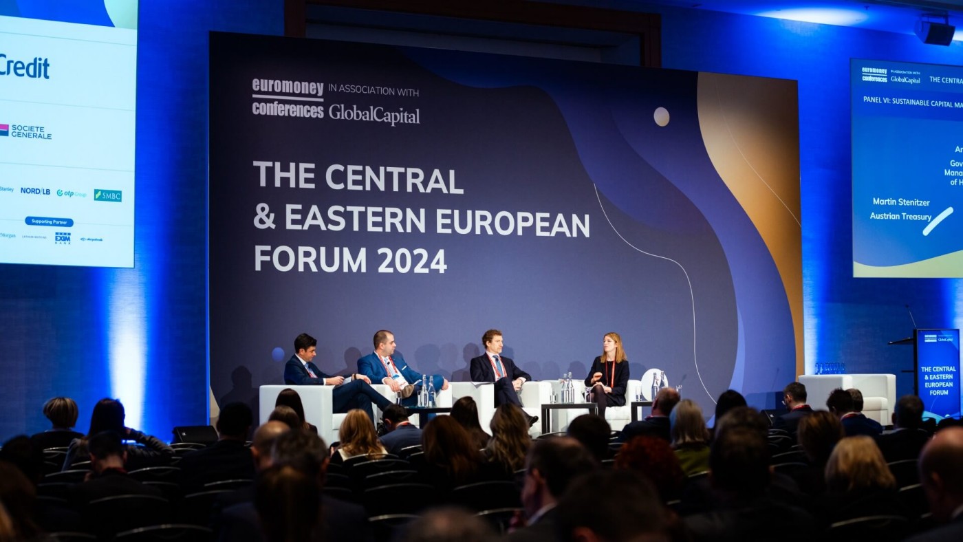Eine Podiumsdiskussion mit vier Rednern auf der Bühne vor einem Publikum beim Central & Eastern European Forum 2024, mit großem Bildschirm und blauer Beleuchtung im Hintergrund.