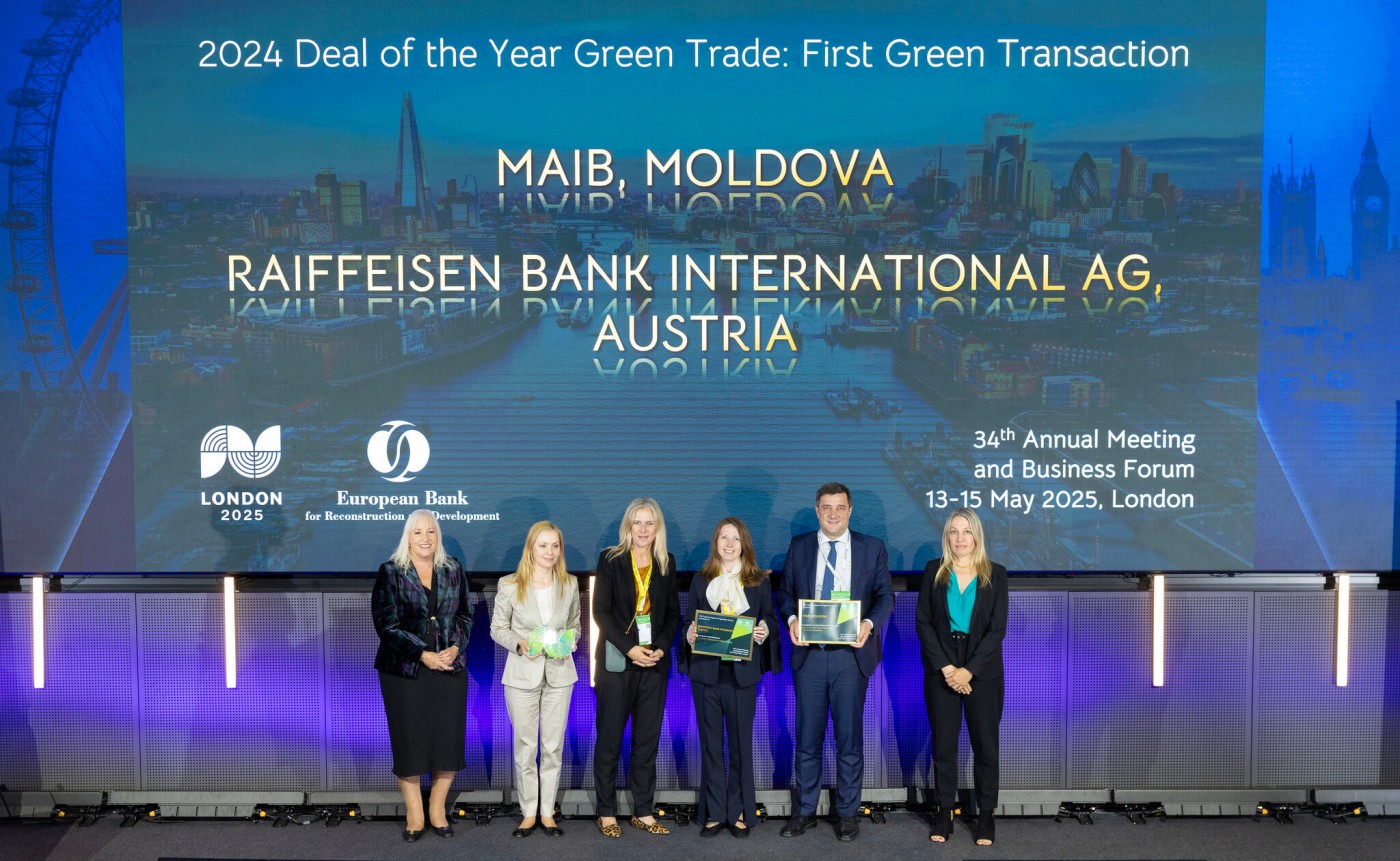 Eine Gruppe von Personen steht auf einer Bühne mit Auszeichnungen vor einer großen Leinwand, die den 2024 Deal of the Year Green Trade für Raiffeisen Bank International AG und MAIB Moldova beim Business Forum in London ankündigt.