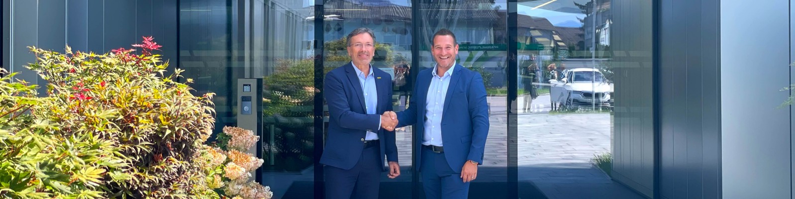 Two business professionals shaking hands outside a modern building, symbolizing a successful partnership.
