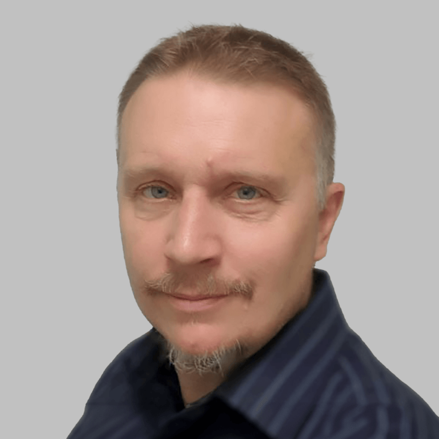 A professional portrait featuring an individual dressed in a blue shirt, set against a neutral background, conveying a formal and polished appearance.