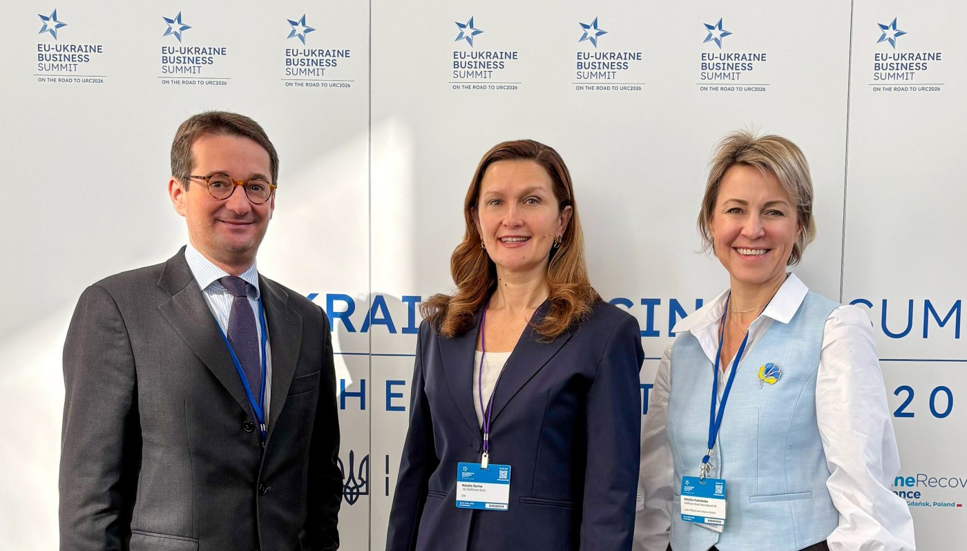 One man, two women in front of a wall at a conference