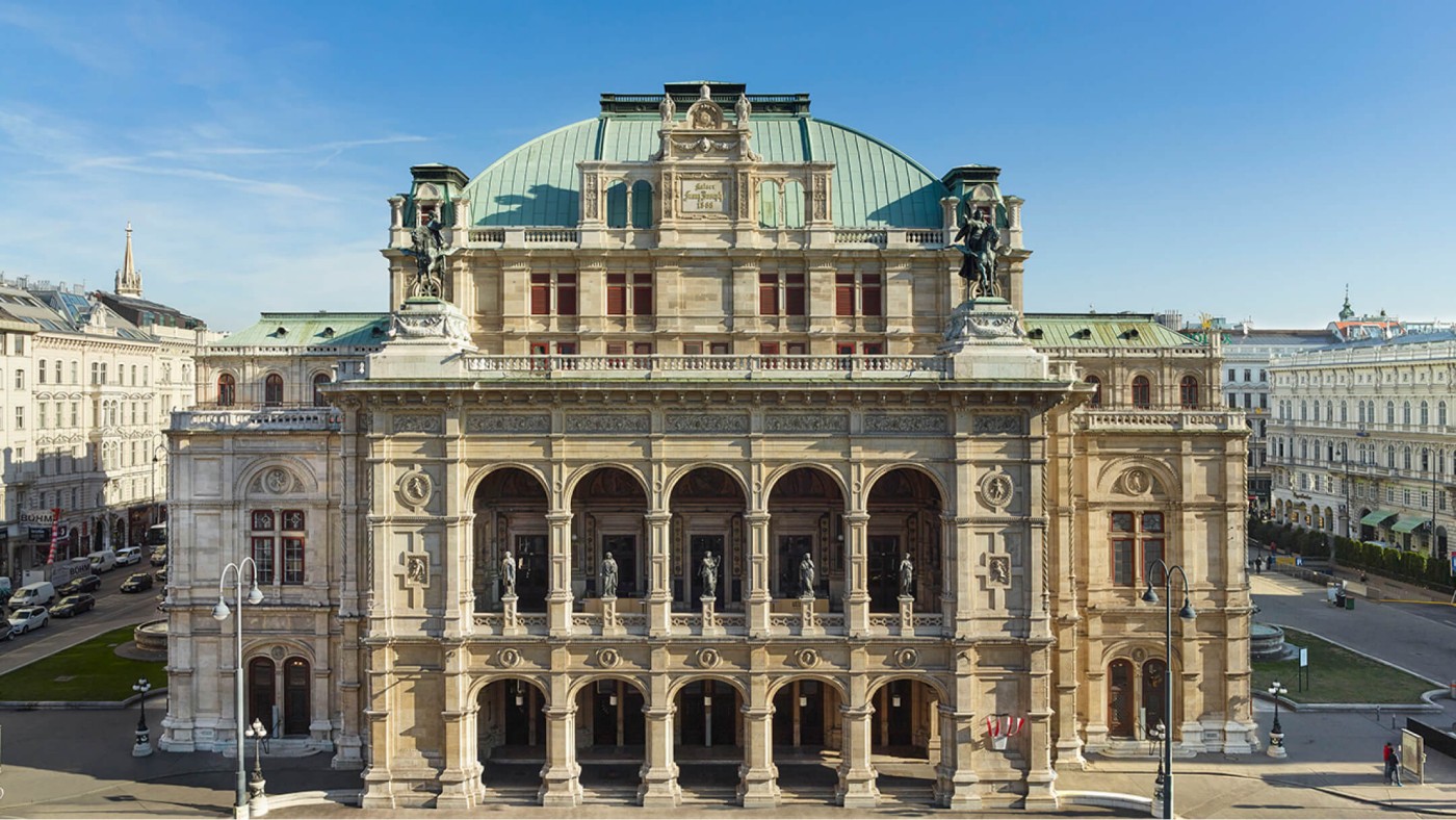 Beeindruckender Blick auf die Wiener Staatsoper mit ihrer prachtvollen Architektur und kunstvollen Details unter klarem, blauem Himmel.