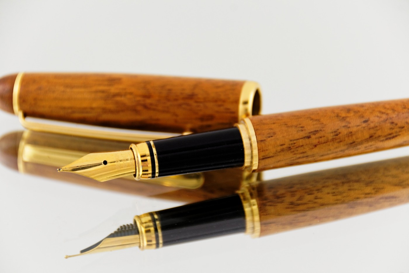 Wooden fountain pen with gold ending in a white backround and white table